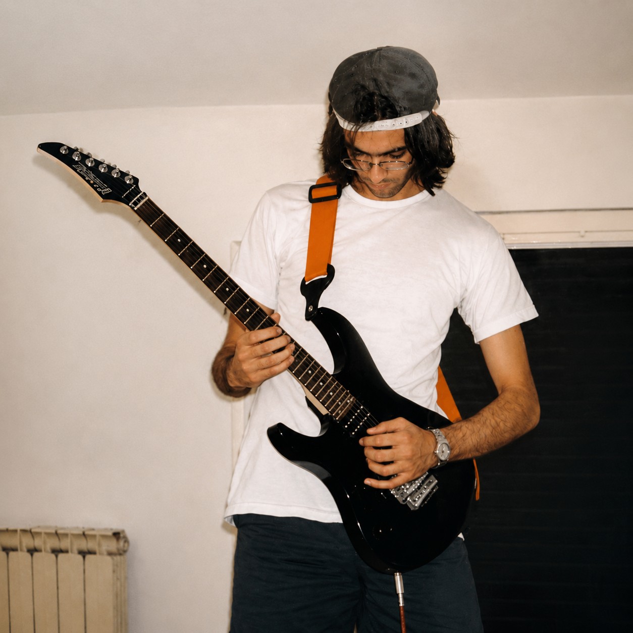 Playing a black electric guitar at home