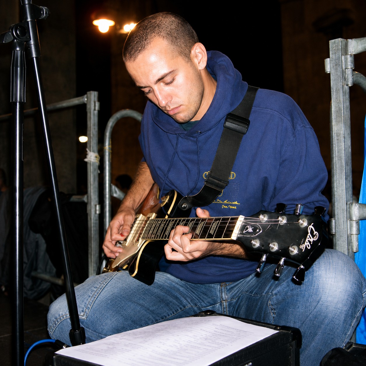 Playing electric guitar at a rehearsal, sheet music on the amp